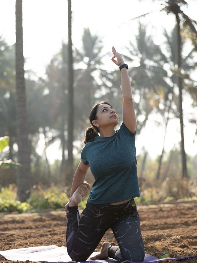 Binita R. Shah practising outdoors at sunrise, kneeling with one arm raised