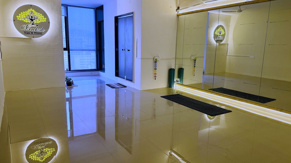 The Vruksh Yoga studio in Baner: mirrored wall, mats laid out, and the backlit Vruksh logo